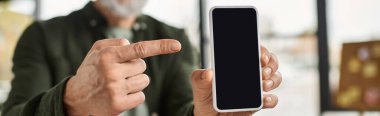 Parlak bir ofiste, birisi akıllı telefonu işaret ederken coşkuyla bilgi paylaşır..