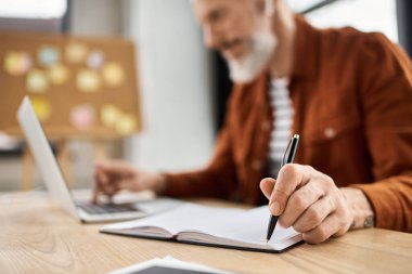 Bir insan parlak ve ilham verici bir ofiste dizüstü bilgisayara notlar alır..