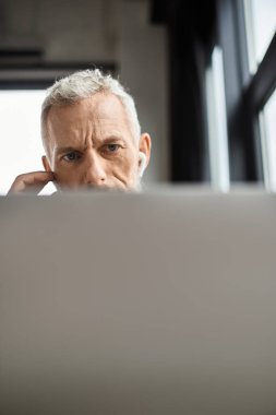 Bir birey, çağdaş bir ofis içindeki görevlere daldırılmış bir bilgisayar üzerinde dikkatle çalışır..