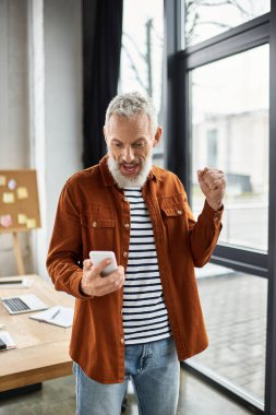 Ofisteki neşeli bir adam telefonundan harika haberler aldıktan sonra heyecanını dile getiriyor.