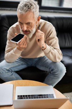 Odaklanmış bir birey şık bir ofis masasında otururken iletişim kurmak için akıllı telefon kullanır..