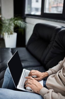 Bitkilerle çevrili şık bir ofis yerinde rahatça otururken dizüstü bilgisayardaki bireysel tipler.