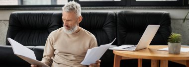 Olgun bir adam şık bir ofis ortamında rahatça otururken evrakları inceler..