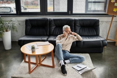 Modern bir ofisteki rahat bir kanepede kıdemli bir profesyonel telefonda konuşuyor..