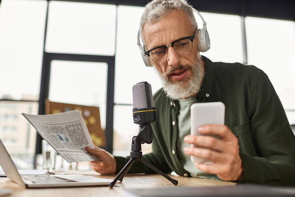 A focused person listens with headphones while reading news and using a mobile device.