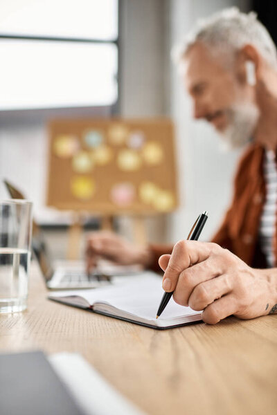 A person brainstorms on a laptop and takes notes in a notebook during work hours.