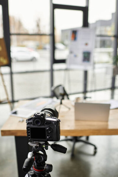 A well organized workspace displays a camera on a tripod next to a laptop and project materials.