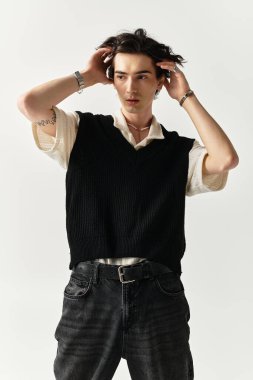 Yakışıklı genç bir adam, minimalist bir arkaplana karşı, modaya uygun bir kıyafetle güven içinde poz veriyor..