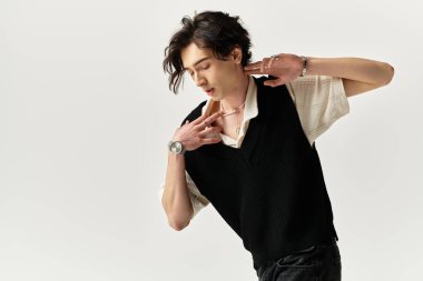 Modayı takip eden genç bir adam, şık kıyafetlerini ve çekiciliğini sergileyerek kendine güvenerek stüdyoda poz veriyor..