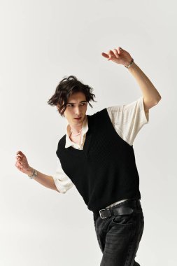 Şık bir genç, modern bir stüdyoda, modaya uygun bir kıyafet ve neşeli bir poz sergileyerek eğleniyor..