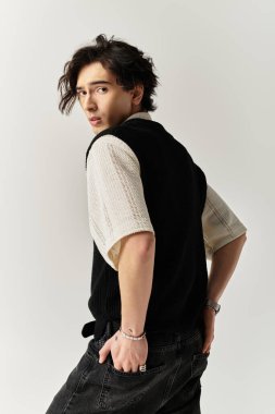 Yakışıklı genç bir adam kendine güvenerek modern moda eğilimlerini yansıtan şık bir kıyafet içinde poz veriyor..