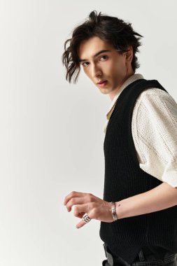 Yakışıklı bir genç, çağdaş bir stüdyoda geçen modaya uygun bir kıyafetle rahatça poz veriyor..