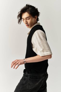 Yakışıklı genç bir adam, modern bir stüdyo ortamında şık kıyafetiyle gösteriş yapıyor..