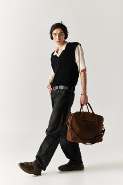 Kendine güvenen genç adam modaya uygun kıyafetini minimalist bir arkaplanda sergiliyor..