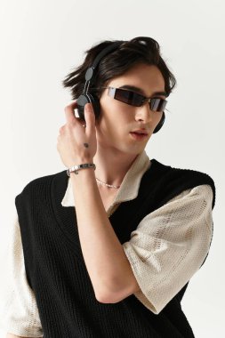 Moda kıyafetli yakışıklı genç adam kulaklık takarken rahatça poz veriyor..