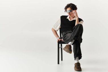 Şık bir genç adam şık bir stüdyoda kendine güvenerek poz veriyor, şık kıyafetlerini sergiliyor..