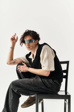 Yakışıklı genç adam, minimalist bir stüdyoda otururken kendine has tarzını sergiliyor..