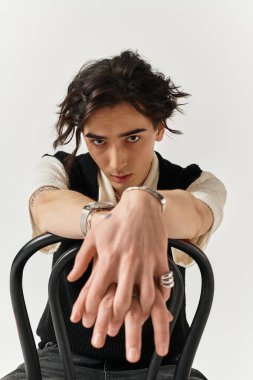 Şık bir genç adam kendine güvenerek poz veriyor, moda anlayışını parlak bir stüdyoda sergiliyor..