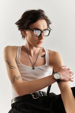 Beyaz atlet giymiş genç bir adam parlak bir stüdyo ortamında şık bir poz veriyor..