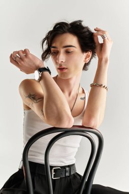 Beyaz atlet giymiş zayıf bir genç adam düşünceli bir şekilde minimalist bir stüdyoda poz veriyor..