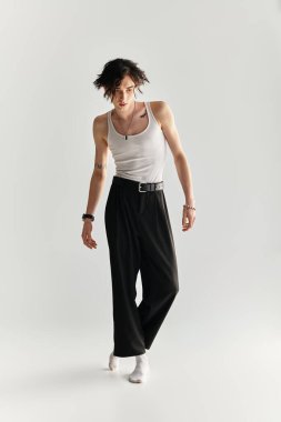 Beyaz askılı genç bir adam parlak bir stüdyoda şık bir görünüm sunar..