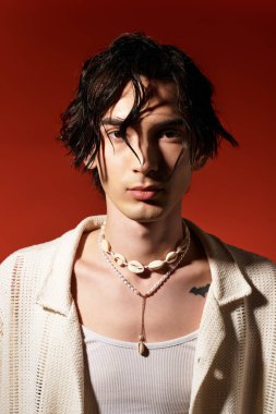 Genç adam yaz tarzını cesur renkler ve özgüvenle bir stüdyo ortamında sergiliyor..