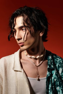 Genç adam modaya uygun bir yaz elbisesi içinde kendine güvenerek poz veriyor, benzersiz tarzını vurguluyor..