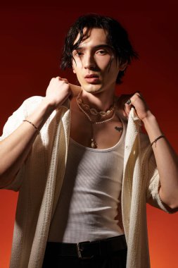 Şık bir genç adam canlı turuncu bir arka plana karşı şık bir yaz kıyafeti sergiliyor..