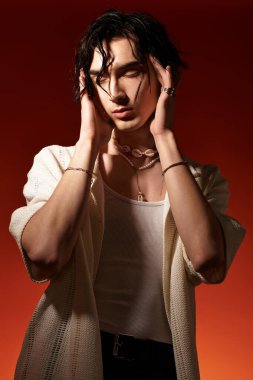 Zayıf genç bir adam, şık bir yaz elbisesi içinde çarpıcı bir arkaplana karşı güven içinde poz veriyor..