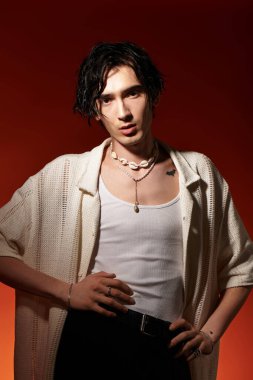 Genç adam, bir stüdyoda güven içinde poz verirken şık bir yaz kıyafeti sergiliyor..