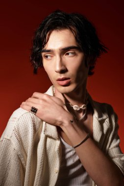 Sıska genç bir adam şık bir yaz elbisesi içinde canlı renklerle güven içinde poz veriyor..