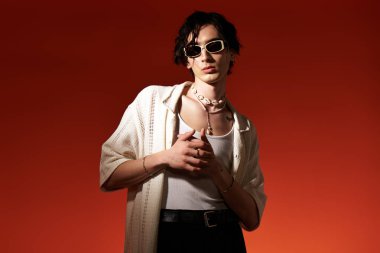 Genç adam canlı arkaplana karşı şık yaz kıyafetleriyle güven içinde poz veriyor..