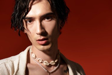 Sıska genç bir adam kendine güvenerek şık bir yaz elbisesi ve eşsiz aksesuarlarıyla poz verir..