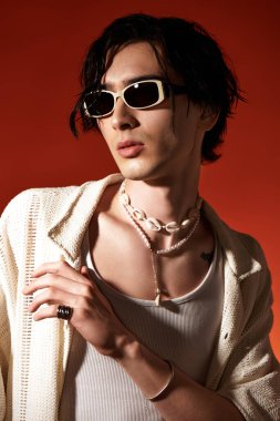 Sıska genç adam bir stüdyo ortamında güven içinde poz verirken şık bir yaz kıyafeti giyer..