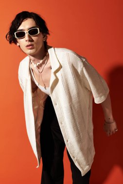 Sıska genç bir adam canlı bir stüdyo ortamında şık bir yaz kıyafeti sergiliyor..