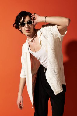 Şık bir genç yaz elbisesi içinde cesur bir turuncu zemine karşı güvenle poz veriyor..