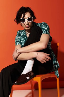 Sıska bir genç yaz kıyafetiyle cesur bir arka plana karşı güven içinde poz veriyor..