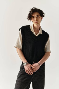 Şık bir genç adam stüdyoda poz veriyor, kendine güveni olan modaya uygun bir kıyafet giyiyor..