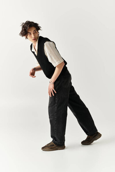 Красивый молодой человек стоит в модном наряде, излучая уверенность и стиль в яркой студии.