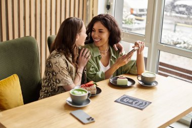 İki kadın tatlı ve kahkahayı rahat bir kafede paylaşıyor, birlikte eğleniyorlar..