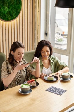 İki kadın kahkahalar ve tatlıları büyüleyici bir kafede paylaşıyor, keyifli anların tadını çıkarıyorlar..