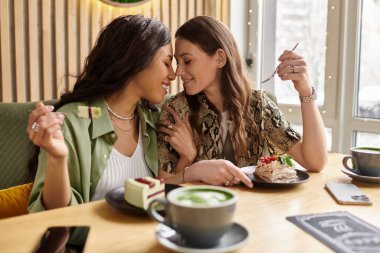 İki kadın, büyüleyici bir kafede tatlı ve kahvenin tadını çıkarırken aynı hassas anı paylaşıyor..