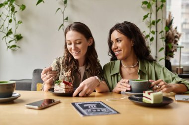 İki kadın tatlı ve kahveden zevk alırken aynı zamanda samimi bir kafede karşılıklı gülüşmeler..