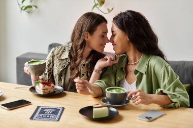İki kadın güzel bir kafe ortamında tatlı ve içki içerken aynı anı paylaşıyor..