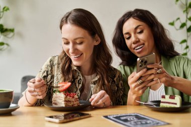 İki kadın bir kafede tatlıdan zevk alır, kahkahalar ve gülücükler..
