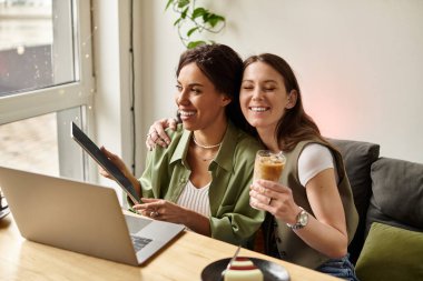 İki kadın birlikte bir kafede vakit geçirir, içkinin ve sıcak gülümsemenin tadını çıkarırlar..