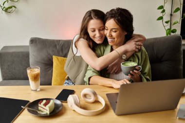 İki kadın bir kafede kahkaha ve sevgi paylaşırken aynı zamanda içki ve ikramın tadını çıkarıyor..