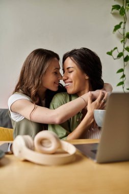 İki kadın, küçük bir kafede sevgi dolu bir şekilde kucaklaşır. Sıcak gülümsemelerle birlikte vakit geçirirler..