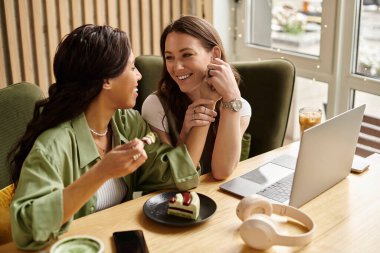 Lezbiyen bir çift, sıcak bir kafede, ahşap bir masada oturmuş tatlıların ve birlikteliğin tadını çıkarıyorlar..