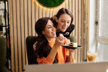 İki kadın, kahkaha ve aşka dalmış büyüleyici bir kafede tatlı yiyorlar..